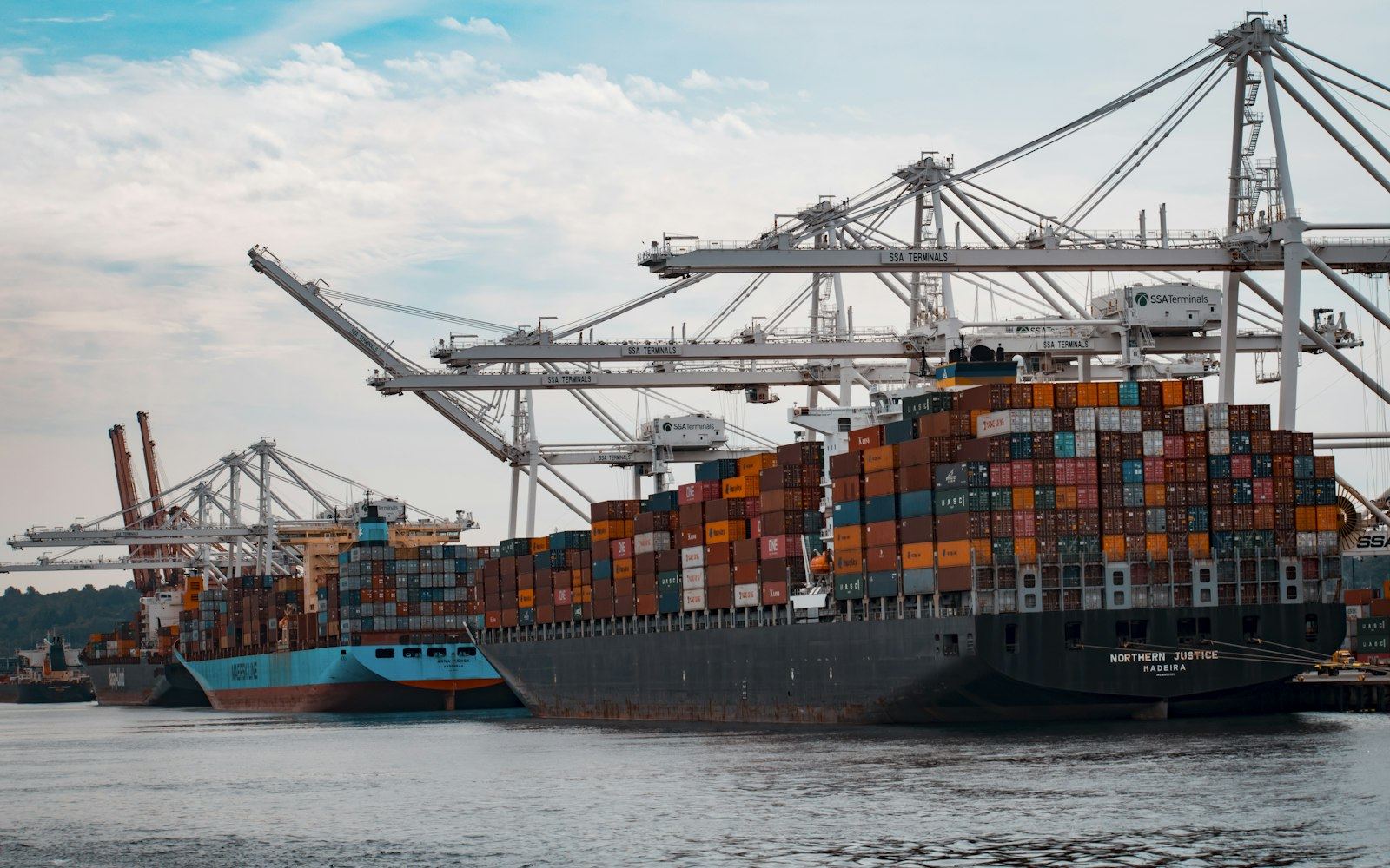A container ship moored at a loading terminal under ship-to-shore cranes